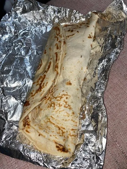 Baleada con Carne - Thick flour tortilla filled with refried beans, cheese, cream, and your choice of meat — the quintessential Honduran street food.